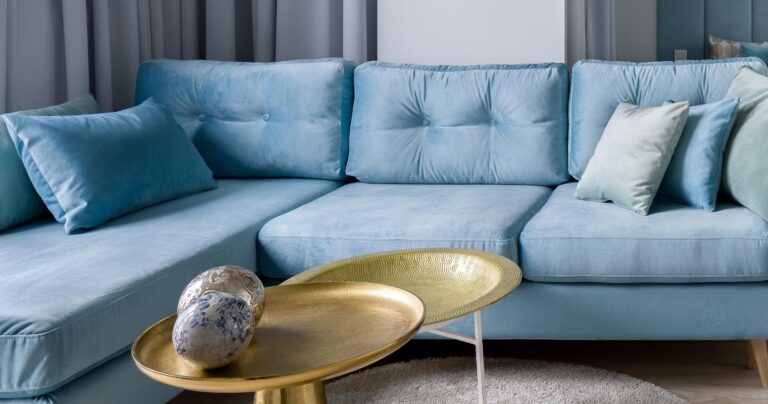Blå chaiselong sofa med guld sofabord. og flotte sofapuder